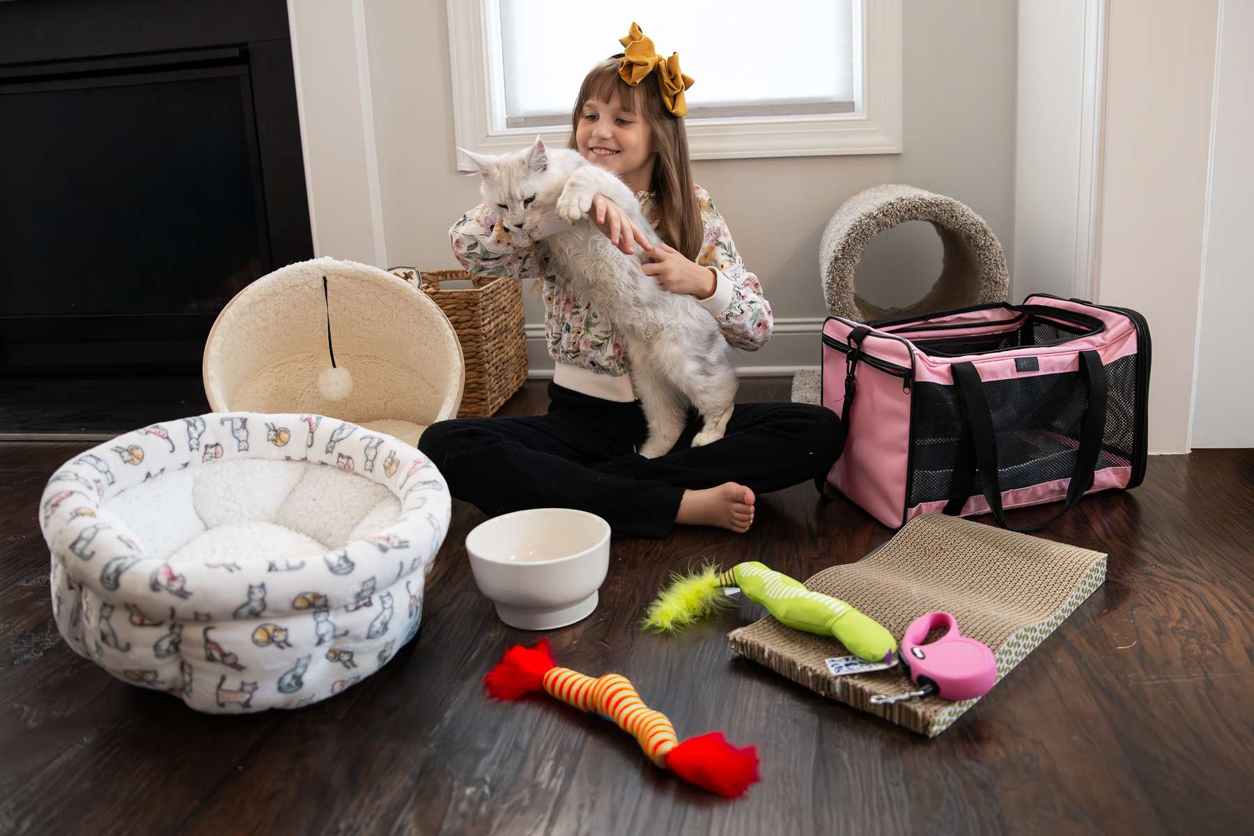 Child holding a kitten surrounded by pet supplies and toys — preparing for a new kitten at Pawzilla Maine Coons.