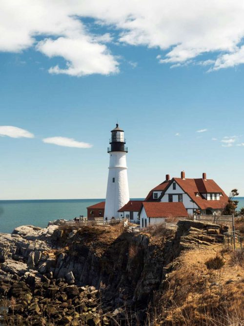 Lighthouse on rocky coast in Maine, USA — birthplace of the Maine Coon cat breed.